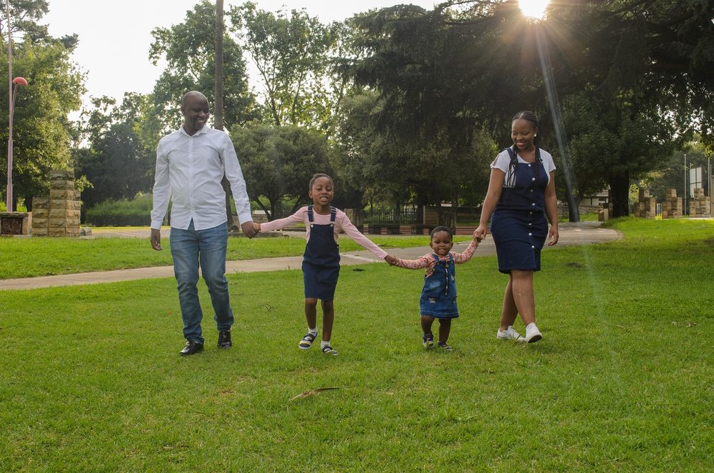A family walking hand in hand together in a sunny park