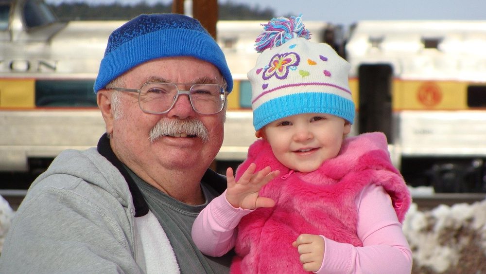 A smiling grandfather holding his young grandchild